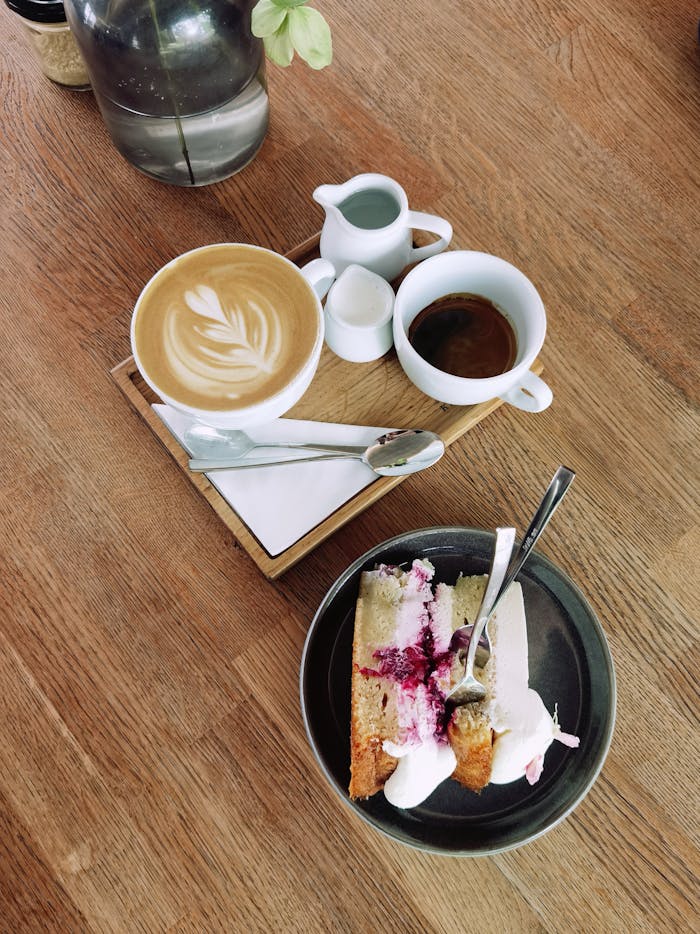 Aerial shot of a latte with art and a slice of cake on a wooden table, perfect for food lovers.